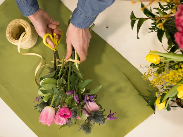 High angle view of male florist hand creating the flower bouquet