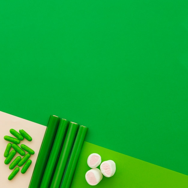 Free photo high angle view of marshmallow, capsule and licorice candies on green backdrop