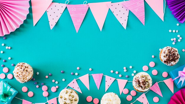 High angle view of muffins with party accessories on green surface