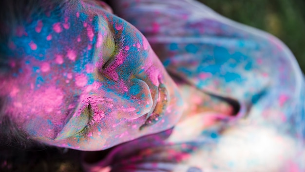 Free photo high angle view of pink and blue holi color on woman's face