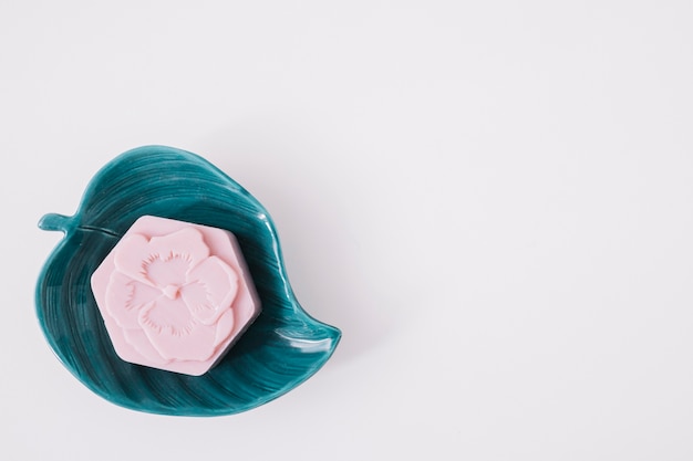 Free photo high angle view of pink soap on leaf shape plate over white surface