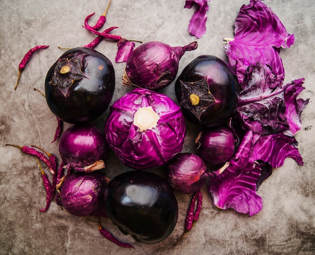 High angle view of purple cabbage; brinjal; onion and red chilies on floor