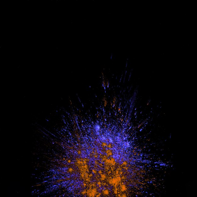 High angle view of purple and orange dust holi colored explosion over black background