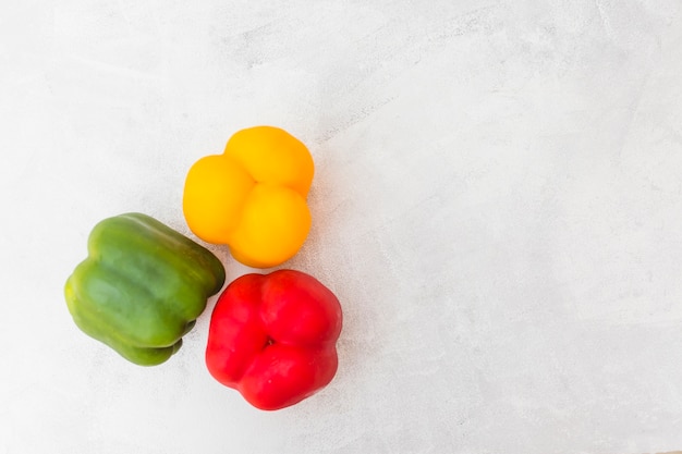 Free photo high angle view of red; green and yellow bell peppers on white background