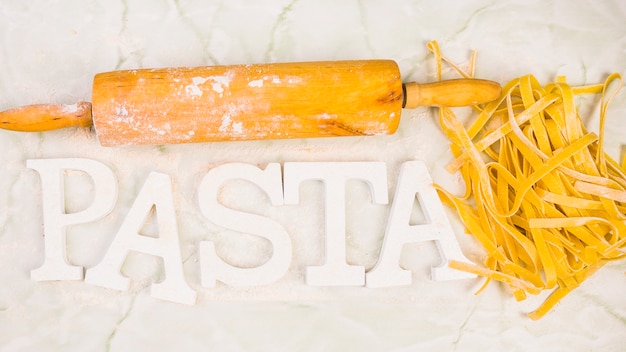 High angle view of rolling pin with pasta and text