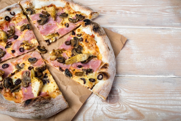 High angle view of sliced mushroom pepperoni pizza on brown paper over wooden table