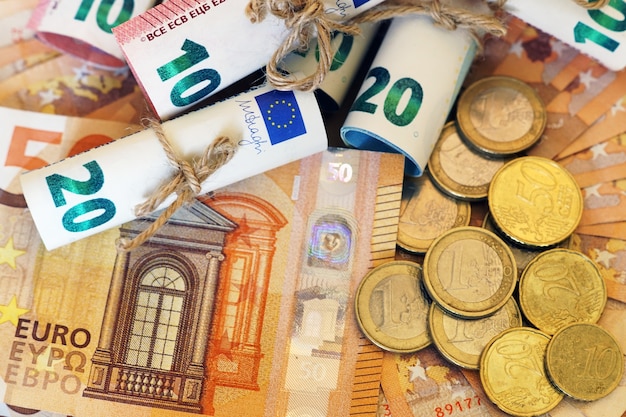 High angle view of some rolled banknotes and coins on more banknotes