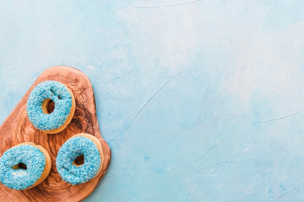 Free Photo high angle view of tasty blue donuts on wooden chopping board