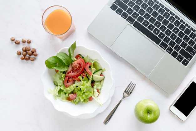 High angle view of tasty breakfast ; laptop and mobile phone on white desk