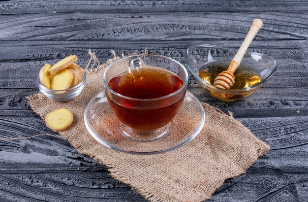 High angle view a tea with ginger and honey on sack cloth and dark wooden background. horizontal