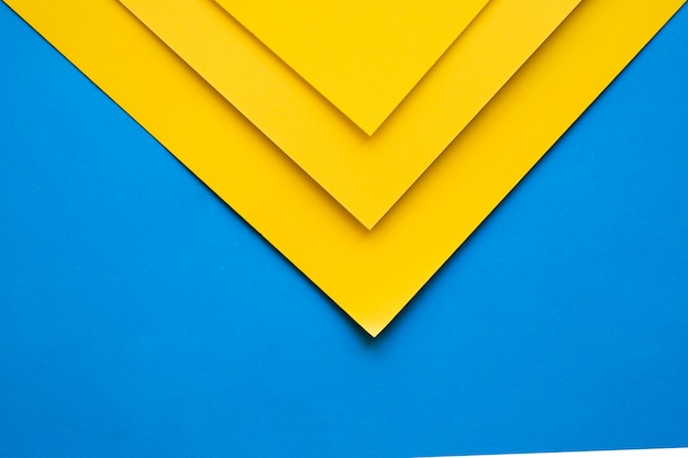 High angle view of three yellow cardboard papers on blue backdrop