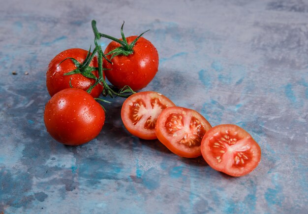 High angle view tomatoes with slices on textured surface. horizontal