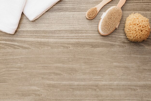 High angle view of towels; sponge and brush on wooden background