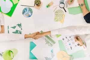 Free photo high angle view of two businesspeople shaking hands over desk