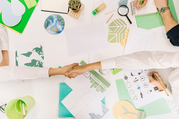 High angle view of two businesspeople shaking hands over desk