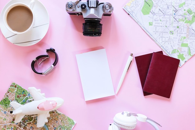 Free Photo high angle view of various traveler accessories with tea cup on pink background