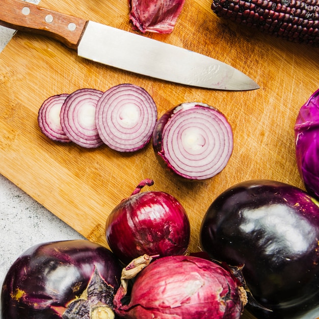 Free photo high angle view of vegetables; sliced onion and knife on wooden chopping board