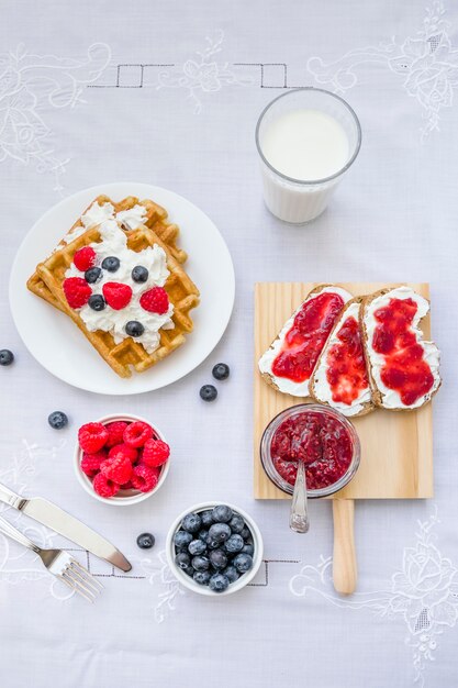 High angle view of waffles with berry fruits and milk