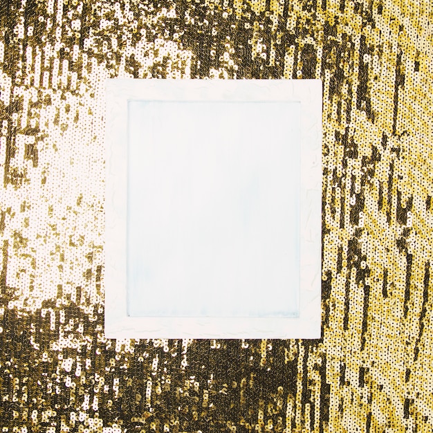 High angle view of white blank frame over shiny sequin backdrop