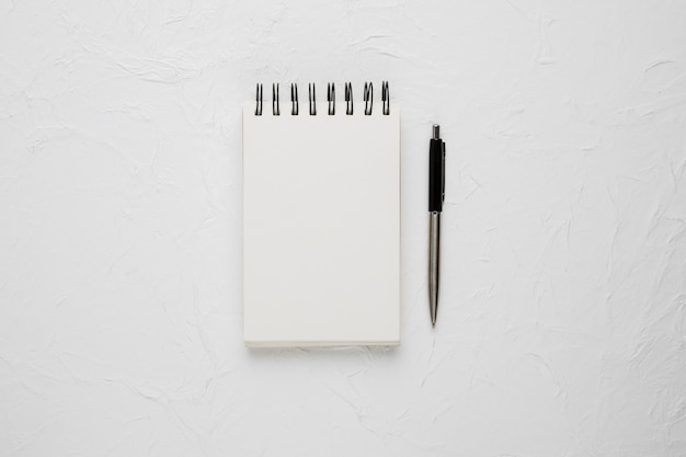 Free photo high angle view of a white blank spiral notepad with ballpoint pen