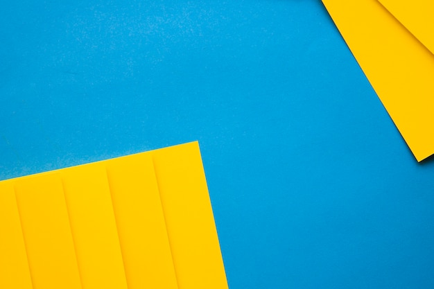 Free photo high angle view of yellow cardboard papers on blue backdrop