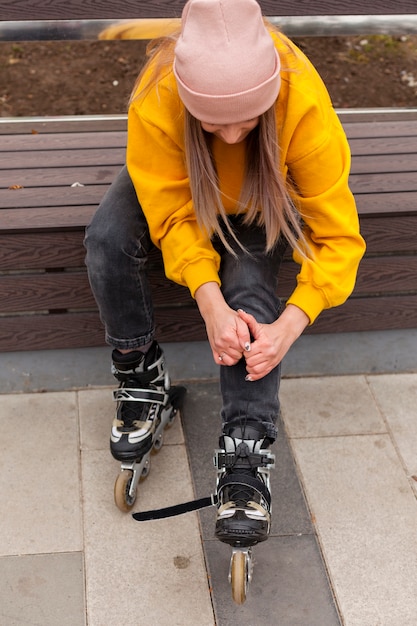 Free photo high angle of woman in beanie adjusting roller blades