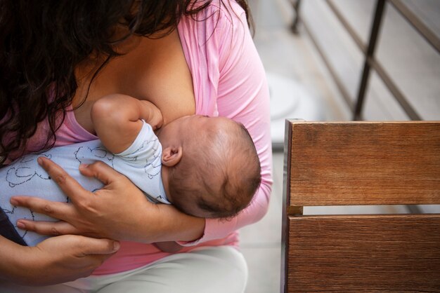 High angle woman breastfeeding  in public