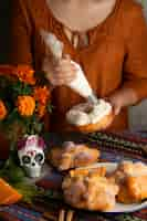 Free photo high angle of woman decorating pan de muerto with cream