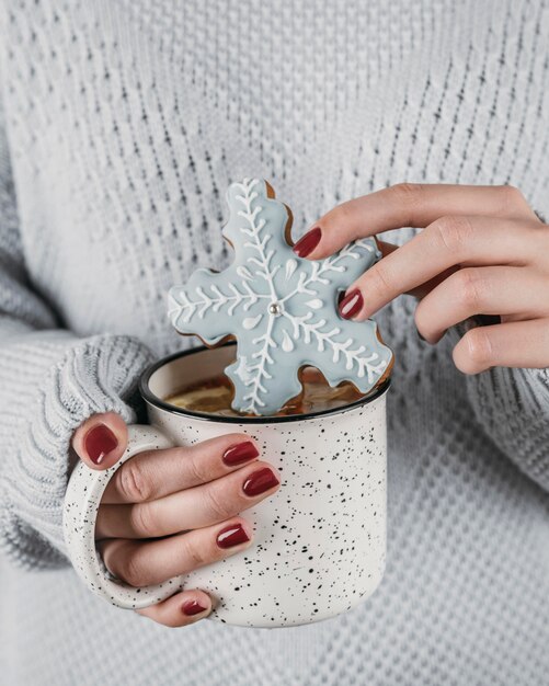 High angle woman dipping snowflake cookie in hot chocolate