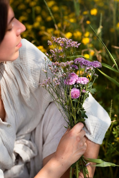 Free photo high angle woman holding purple flowers