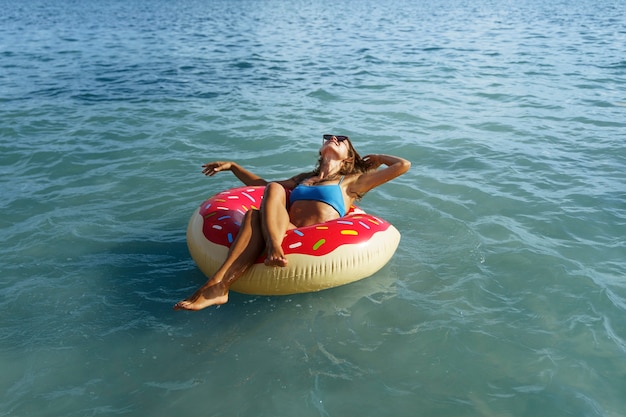 Free photo high angle woman laying on doughnut floater