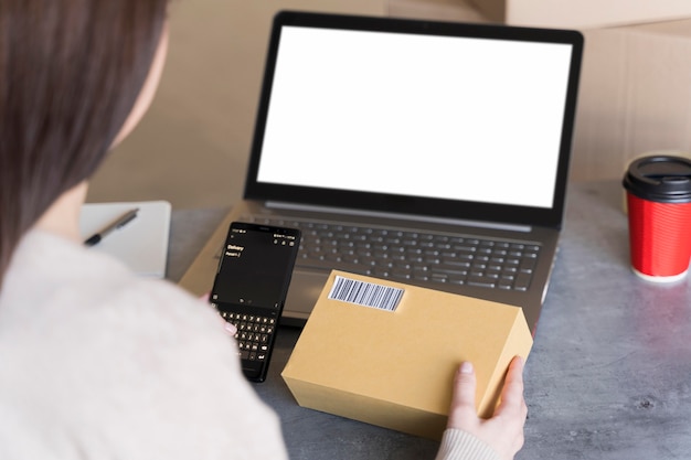 Free photo high angle of woman looking up bar code on box she's holding