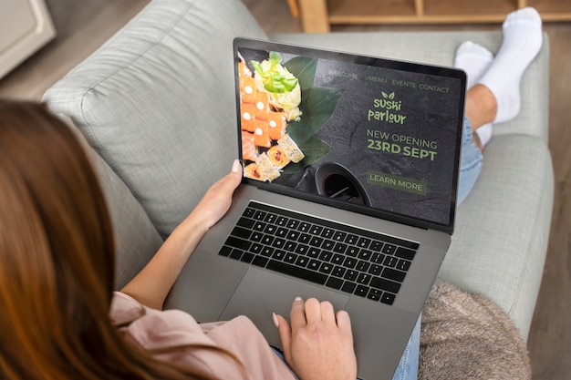 Free photo high angle woman ordering sushi with laptop