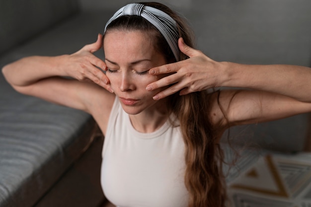 Free photo high angle woman practicing facial yoga