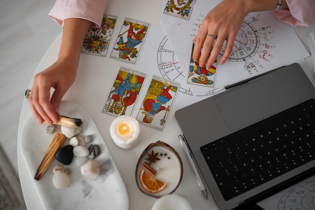 High angle woman reading tarot with laptop