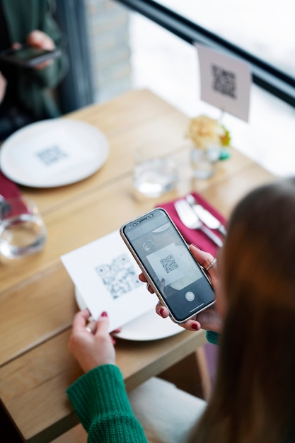 Free Photo high angle woman scanning qr code at restaurant