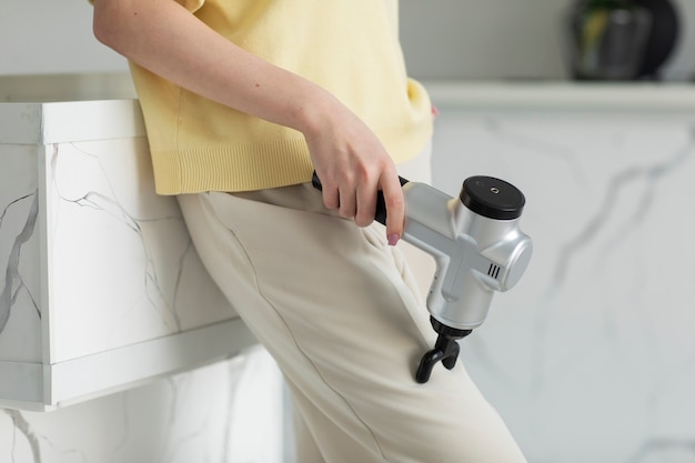 Free Photo high angle woman using massage gun