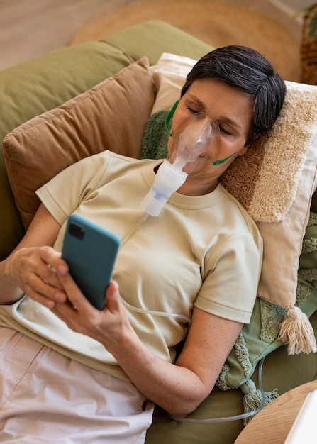 Free photo high angle woman using nebulizer