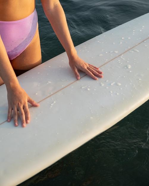 Free photo high angle of woman with surfboard on water