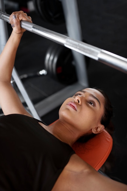 Free photo high angle woman working out with barbell