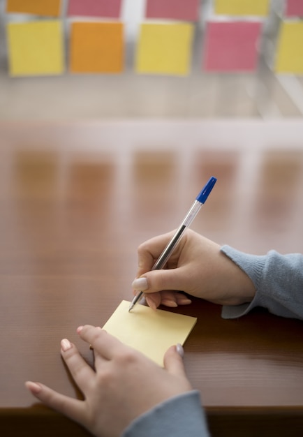 High angle of woman writing on sticky notes while at the office