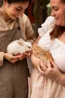 Free photo high angle women holding cute bunnies