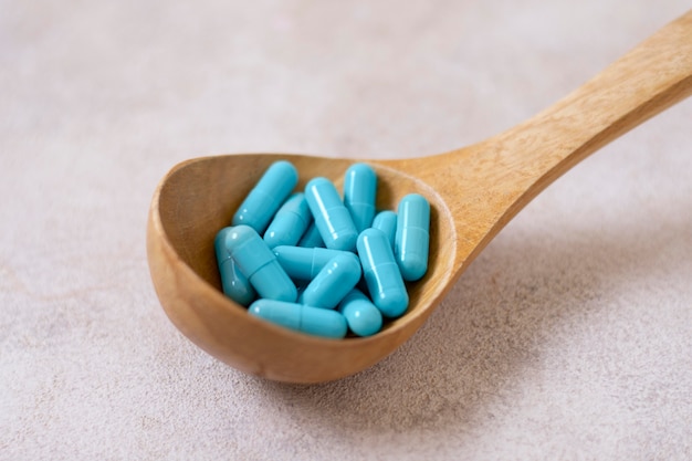 Free photo high angle wooden spoon with blue pills