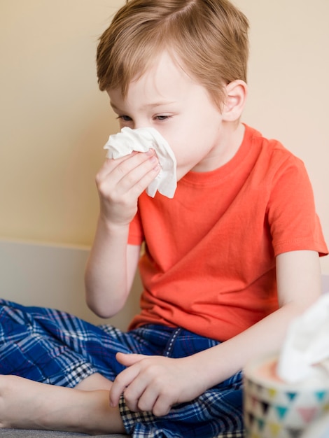 High angle young boy blowing his nose