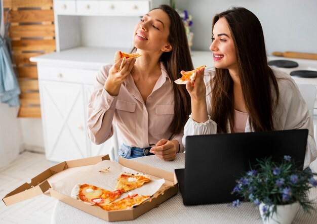 High angle young women eating pizza