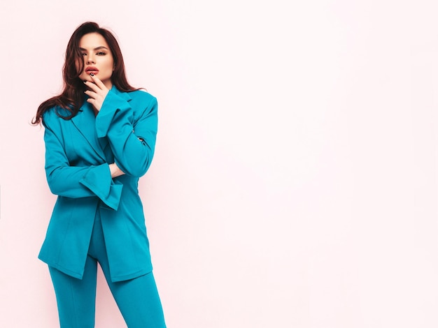 High fashion portrait of young beautiful brunette woman wearing nice trendy blue suit Sexy fashion model posing in studio Fashionable female isolated on light pink