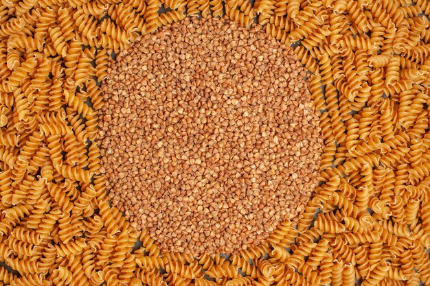 High resolution photo of buckwheat in the middle of raw Italian pastas lined circle frame overhead view