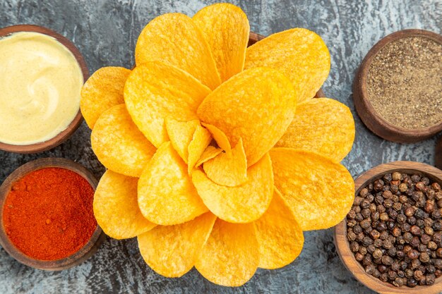 High resolution photo of homemade potato chips decorated like flower shaped in a brown bowl on gray table