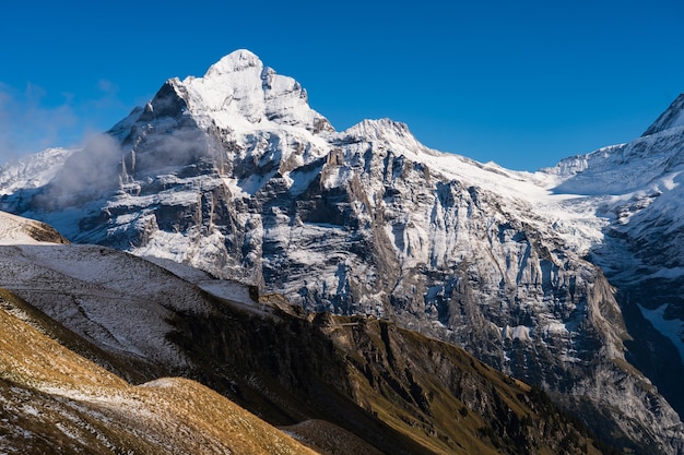 High rocky mountains covered with snow under a clear blue sky in Switzerland