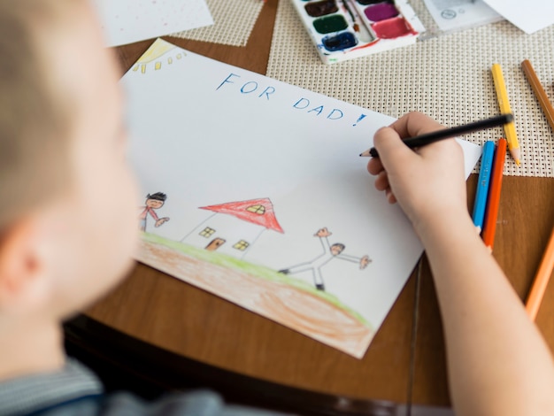 High view child and drawings for his father